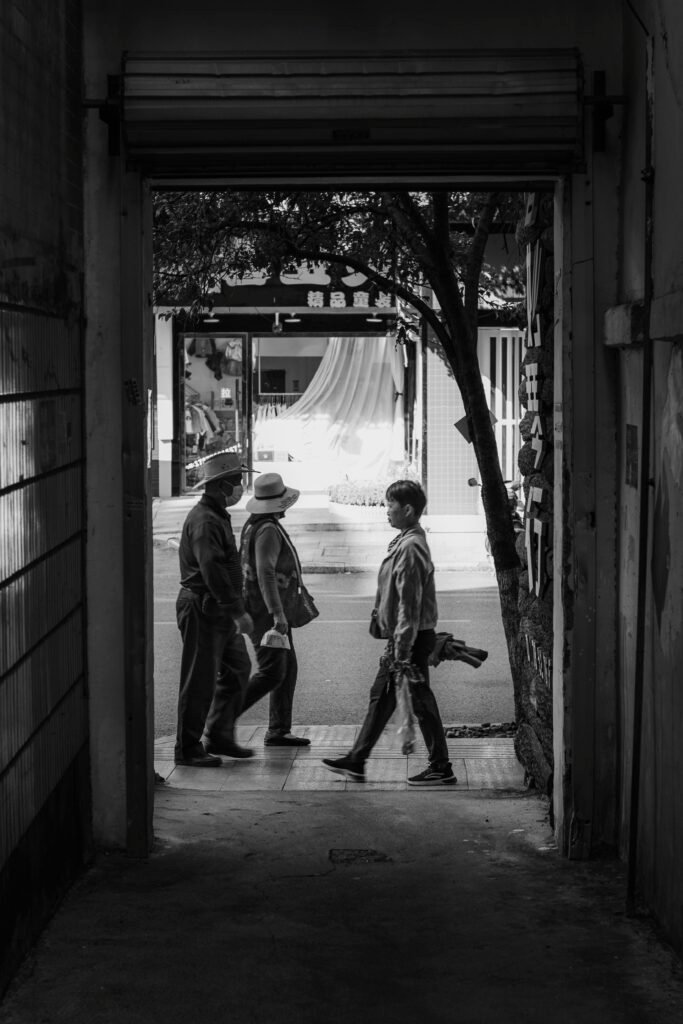 Monochrome image of pedestrians walking through a city gateway, capturing a candid urban moment.